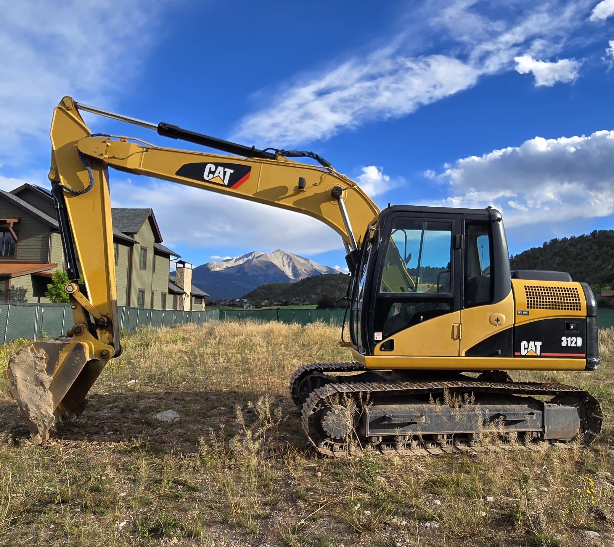 A yellow and black cat tractor in the grass.