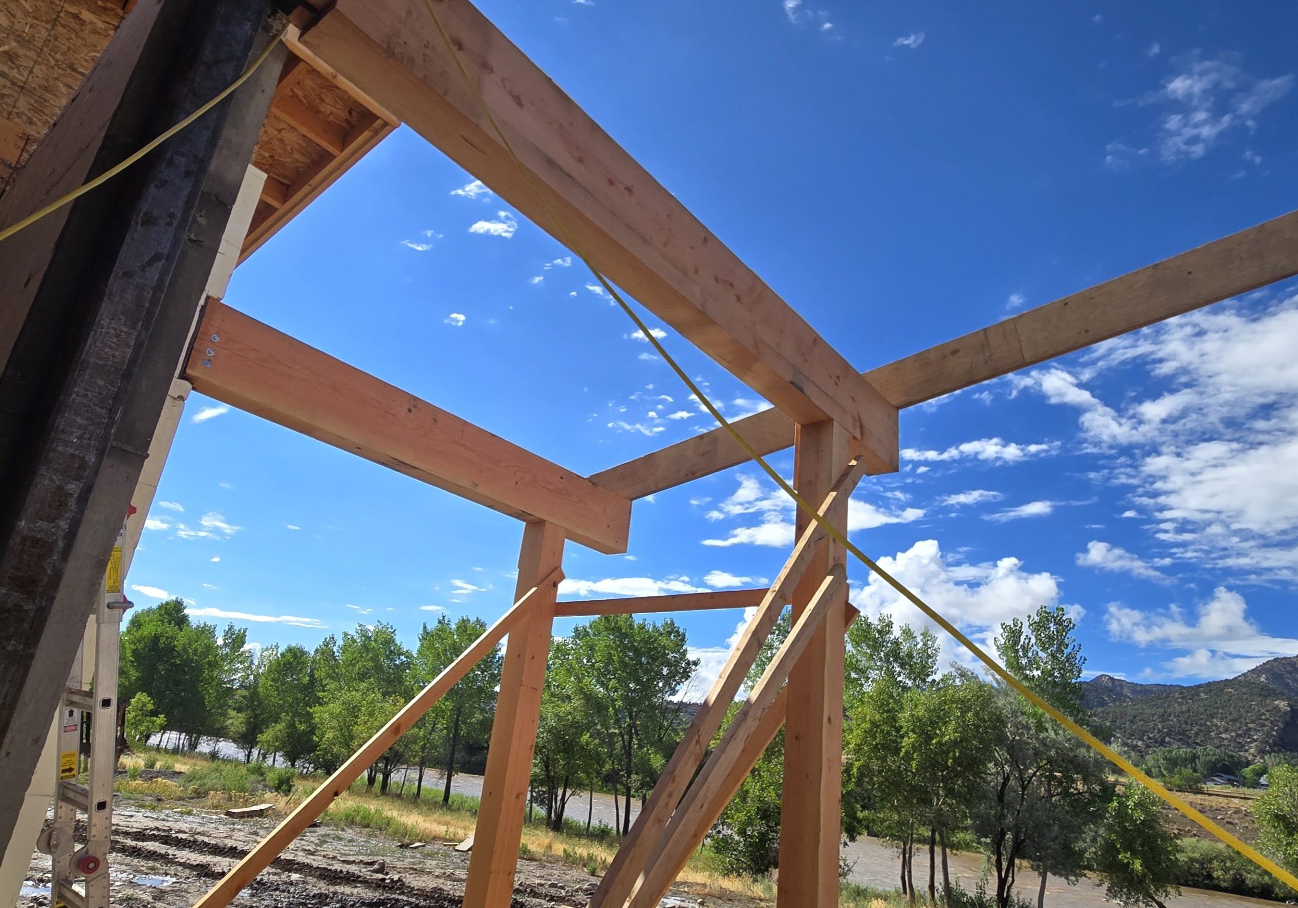 A wooden structure under construction with trees in the background.